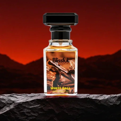 Blissful White Ball perfume bottle with cinnamon sticks, set against a red sunset mountainous background