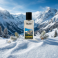 Blassh Kashmer perfume bottle on snow with pine branches, snowy mountain landscape in background