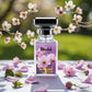 Blissful Blue Lady Eau de Parfum bottle with pink flowers on table and branches in soft outdoor background