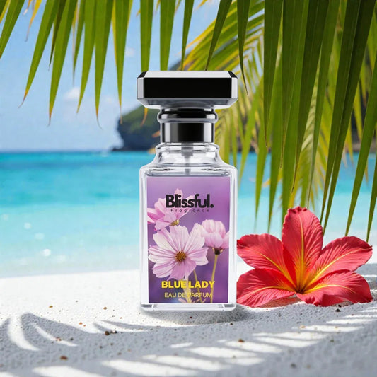 Blissful Blue Lady eau de parfum bottle on sandy beach with tropical palm leaves and red hibiscus flower