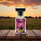Blissful Queen of Hearts perfume bottle on wooden table with sunset and field background