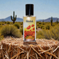 Blissful Floral Temptation perfume bottle on straw bale with desert cacti and mountains background
