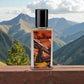 Blisstol White Ball perfume bottle on wooden surface with mountain landscape background